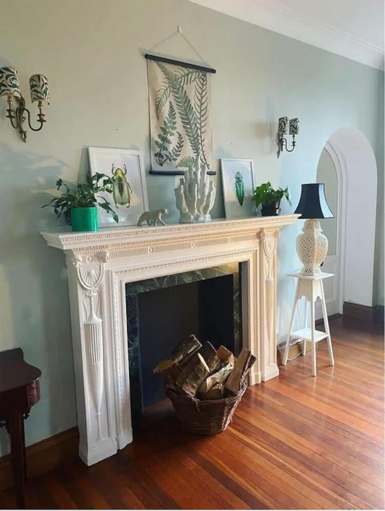 The drawing room, with a white fireplace and a basket of logs