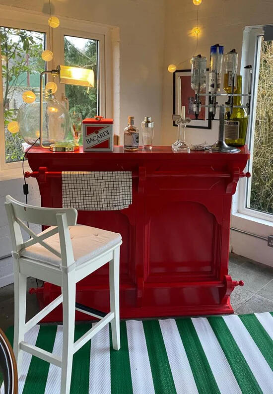 The Little Red Bar in the sunroom, with bar stools and glasses
